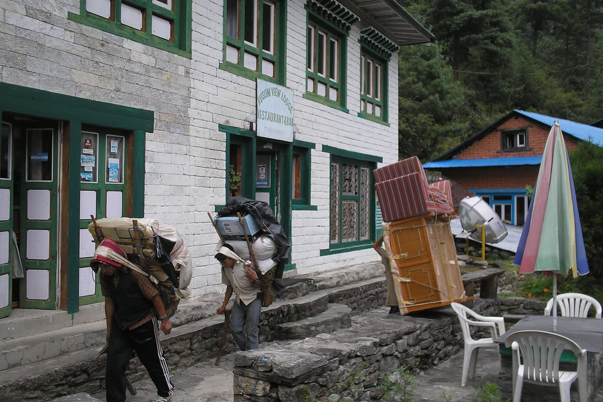 Porters carrying furniture and supplies outside a Khumbu lodge