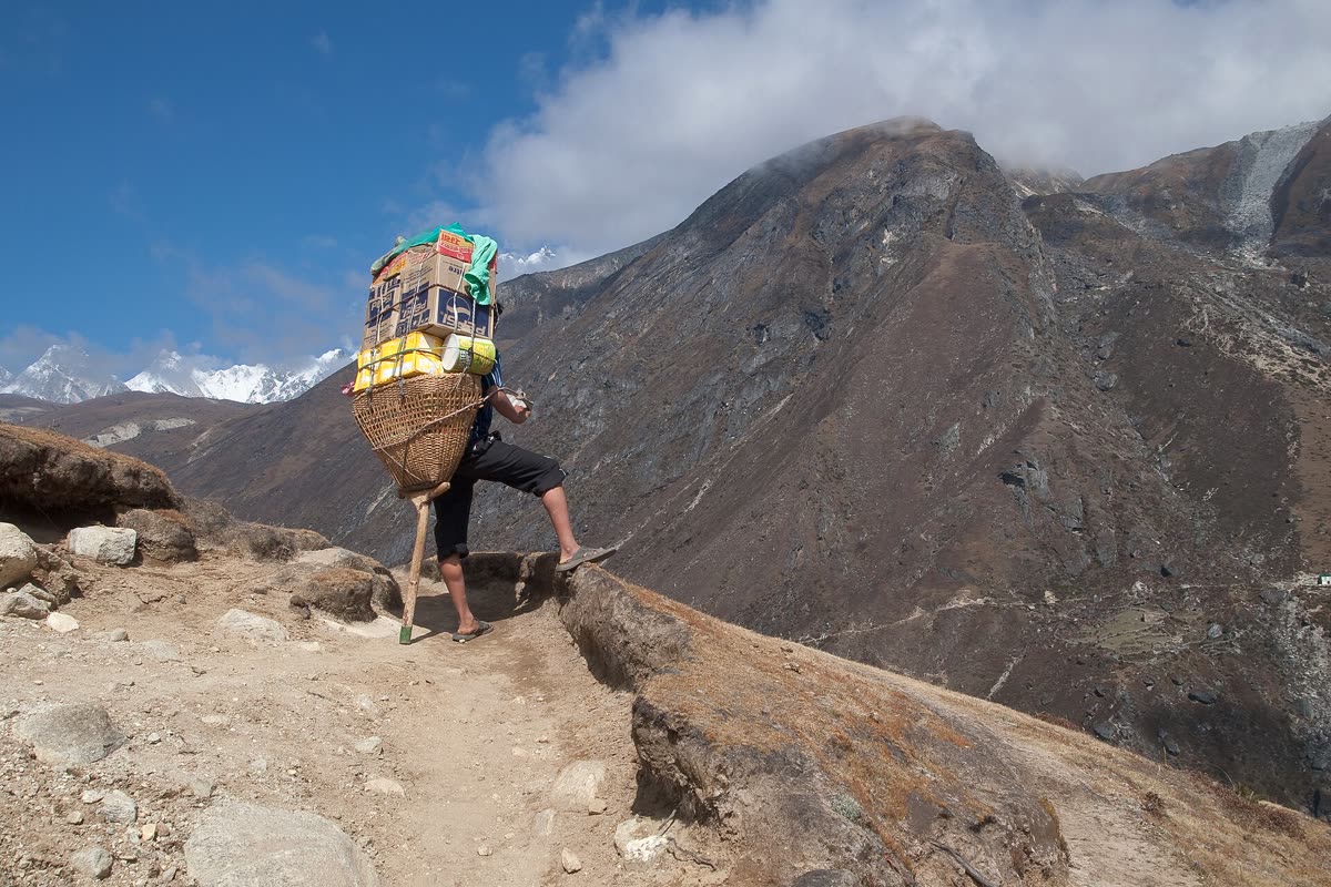 A porter carrying a heavy load along a high ridge in the Khumbu