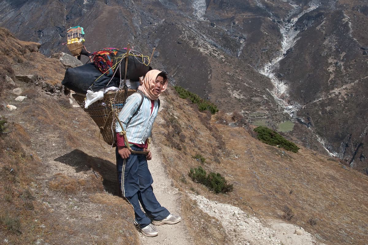 A porter resting with a load on a trail in the Khumbu, Nepal